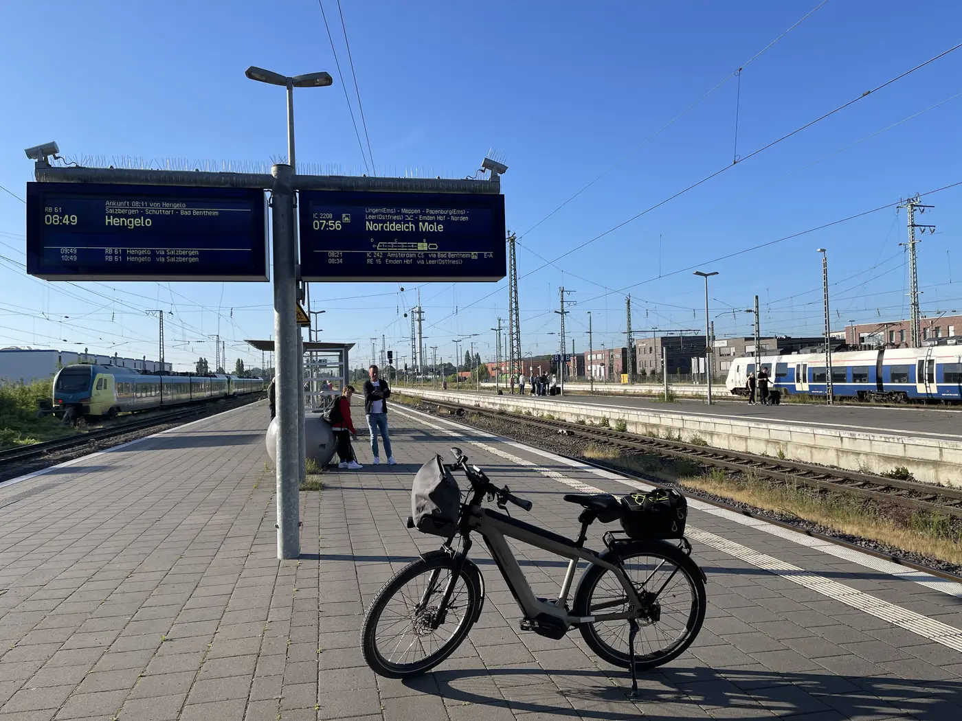 Das Rad auf dem Bahnsteig in Rheine, auf der Anzeigetafel steht die Abfahrt nach Norddeich um 07:56 Uhr