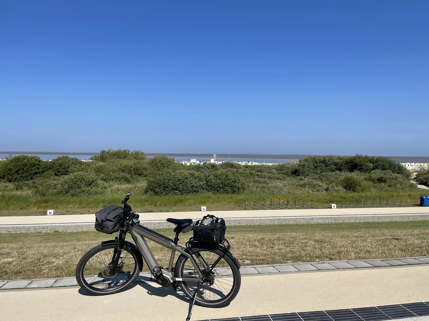 Das bepackte Rad am Deichweg, dahinter Grünland und Nordsee